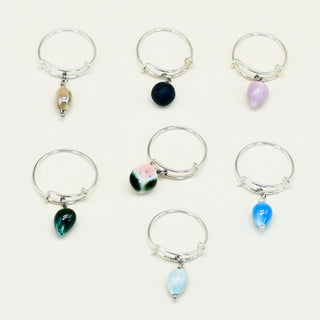 Set of eight silver adjustable rings with colorful porcelain gemstone charms on a white background