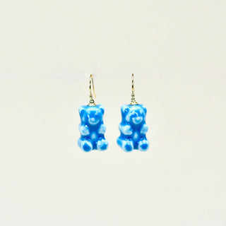 Blue gummy bear porcelain earrings on a light beige background