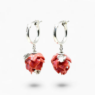 A pair of silver hoop earrings with dangling rose-shaped charms in a glossy pinkish-red enamel finish, shown on a clean white background.