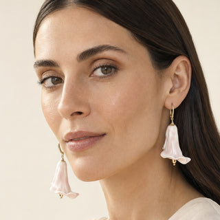 A close-up of a woman wearing delicate, calla lily-shaped dangle earrings made of pale pink porcelain with gold-filled leverbacks - perfect gift for wedding anniversary