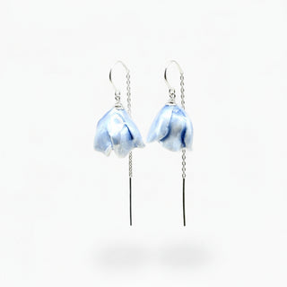 A pair of sky blue dangle earrings with mother of pearl marbled peony-shaped charms and long black dangling threaders, shown on a plain white background.
