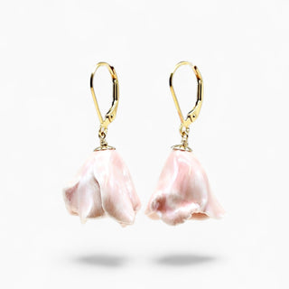 A pair of gold leverback earrings with dangling light pink flower-shaped charms, shown against a plain white background.