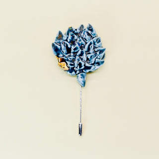 Blue green porcelain handmade artichoke floral lapel pin brooch on a beige background
