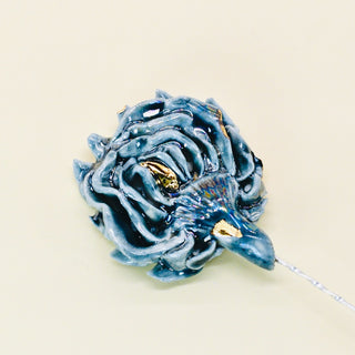 Blue porcelain ceramic artichoke flower brooch on a beige background