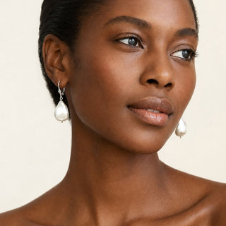 Dark-skinned woman wearing pearlescent white baroque pearl porcelain drop earrings by FARPHORIA