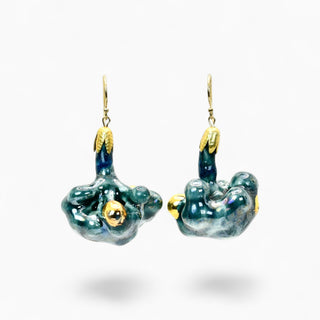 A pair of dangling earrings with organic, -flower shapes in glossy dark teal and blue enamel, accented with gold-toned details and hooks, shown on a clean white background.