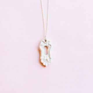 Necklace with a unique key-shaped porcelain pendant on a pink background
