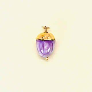 Purple acorn seed porcelain pendant with gold accents on a beige background