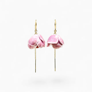 A pair of gold-tone dangle earrings featuring pink flower petals, suspended from thin gold chains with fishhook backings, shown against a plain white background.