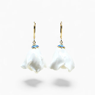 A pair of dangling earrings with irregular white pearl-like flower shapes, gold hooks, and small blue floral accents at the top, shown on a clean white background.